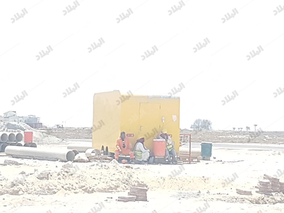 عمال يستريحون في ظل عربة مهجورة